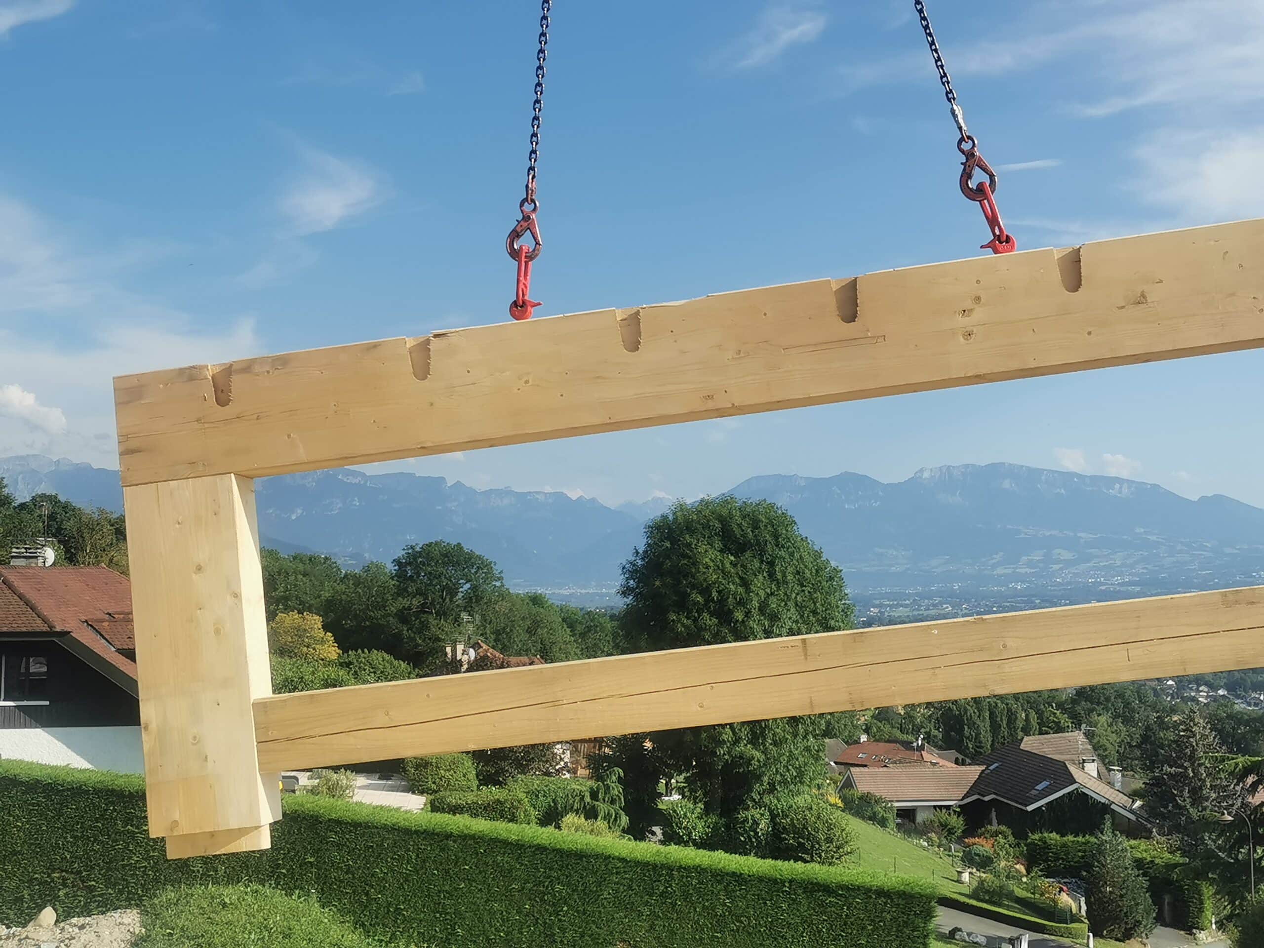 élément vertical en bois soulevé à l’aide d’un treuil lors du montage de la structure d’un bâtiment