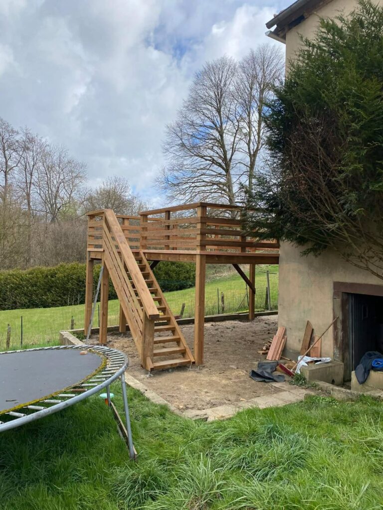 Terrasse en bois surélevée avec escalier donnant accès au jardin.