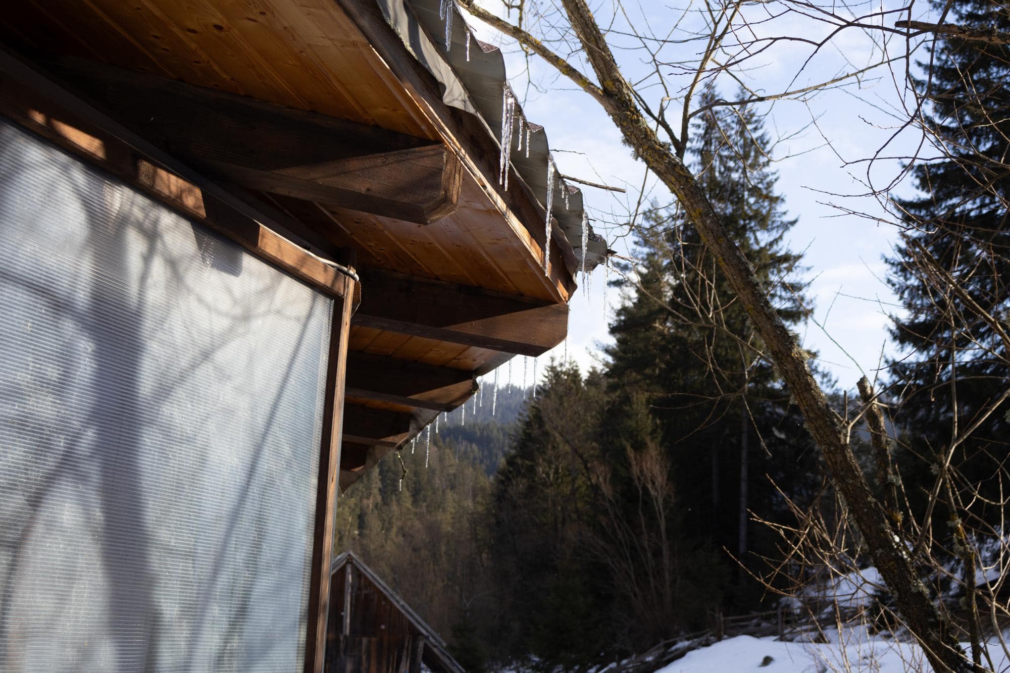 Chalet en bois sous la neige dans un paysage de montagne.